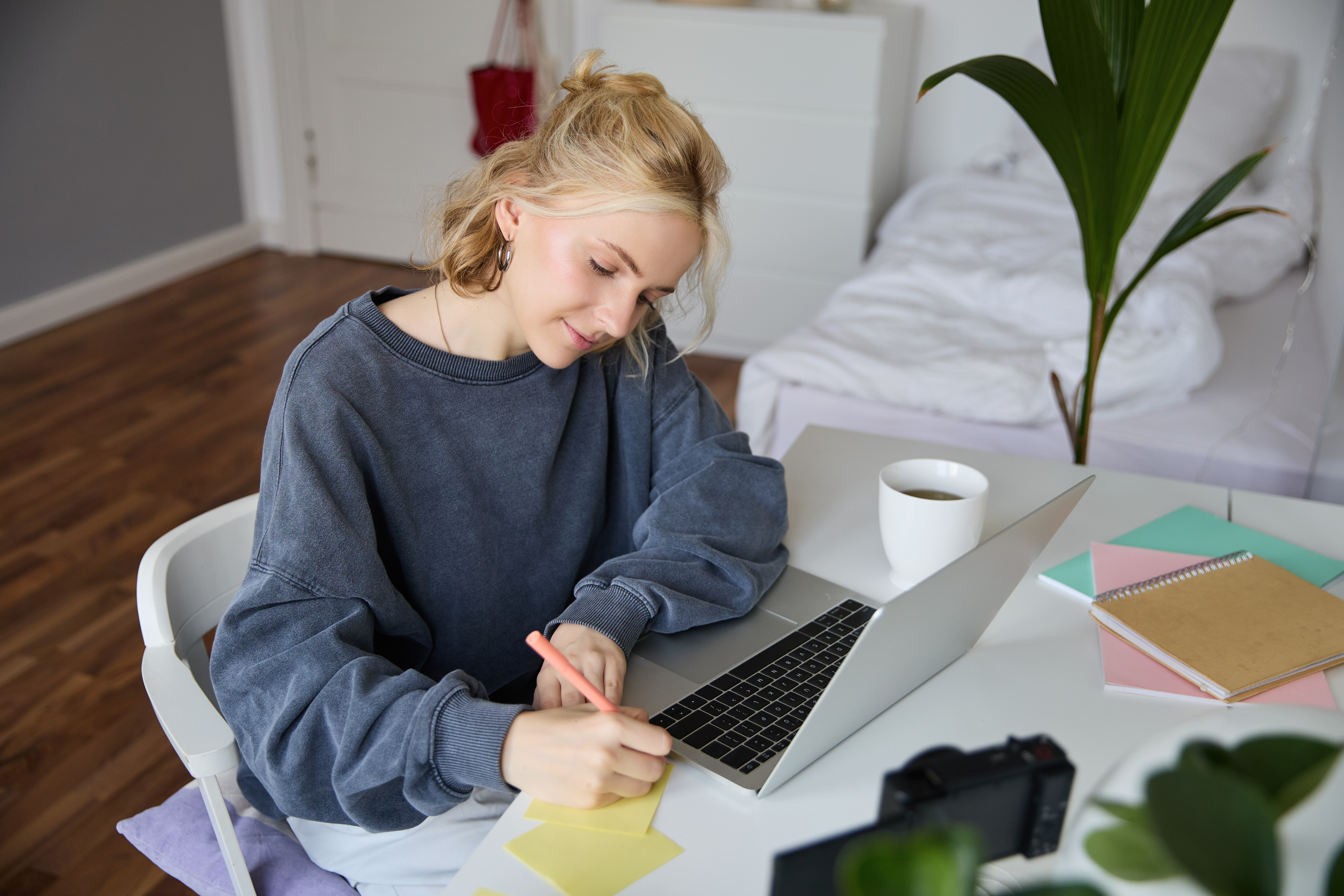 international-student-in-the-netherlands-writing-on-paper-in-her-student-room-furnished-on-a-budget